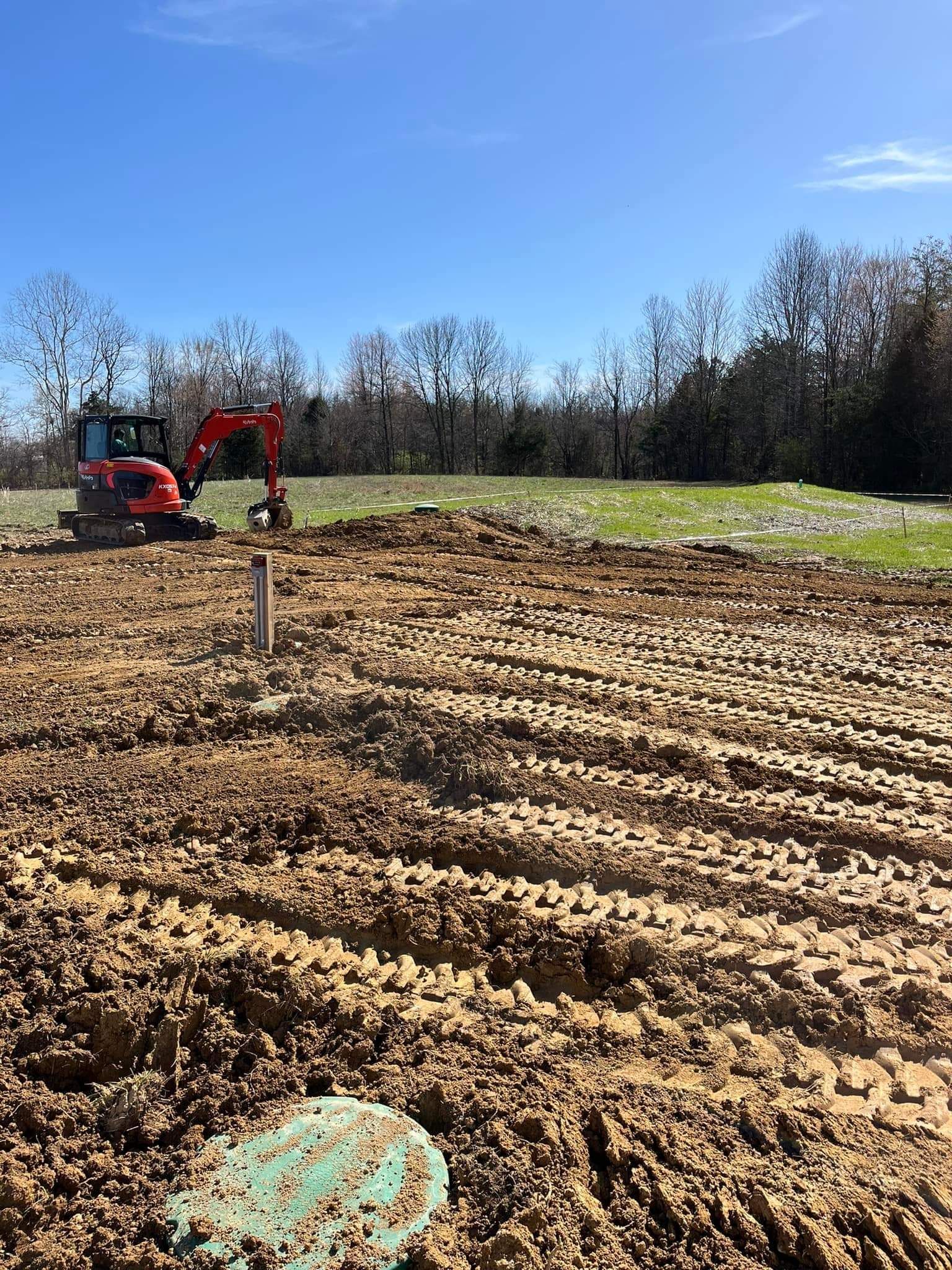 A large pile of dirt in a field with trees in the background.