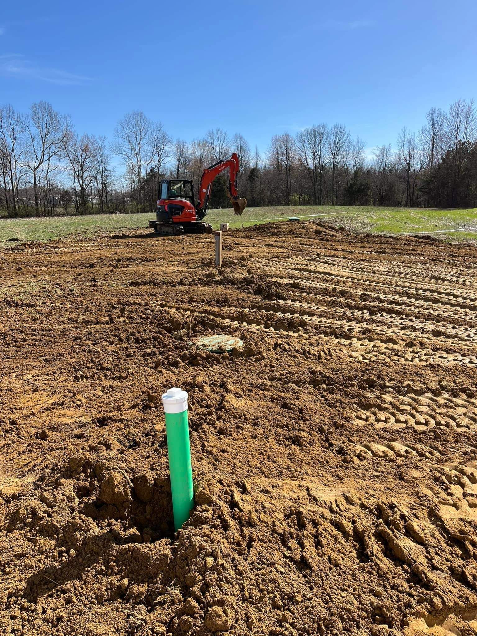 A large pile of dirt in a field with trees in the background.
