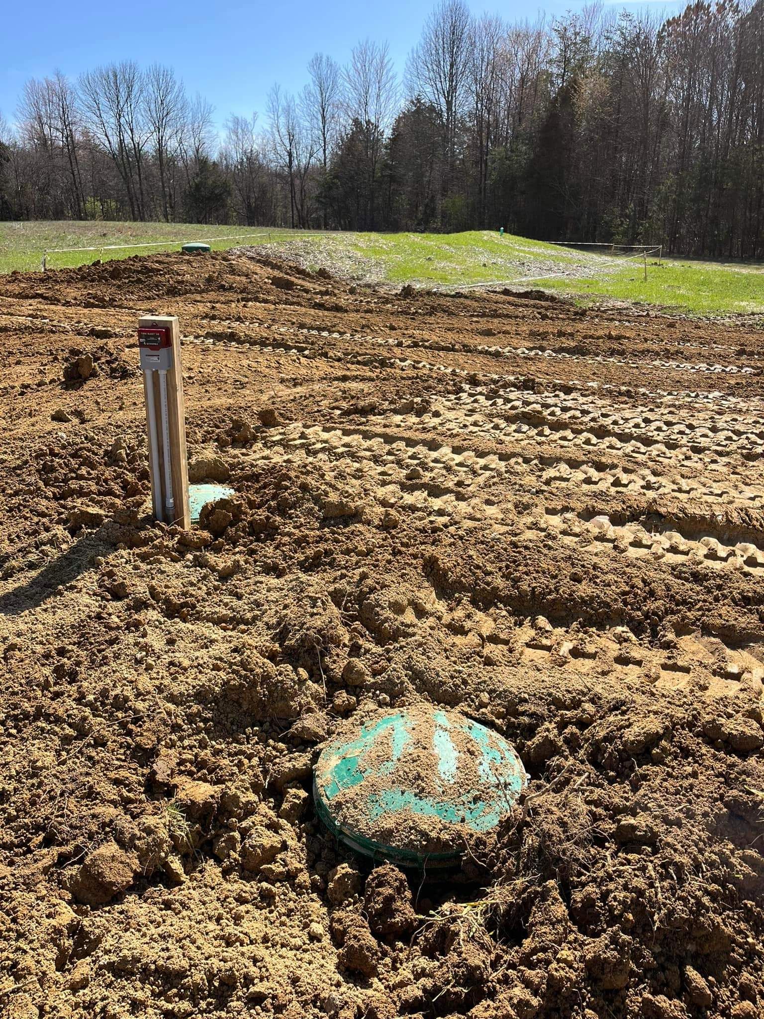 A large pile of dirt in a field with trees in the background.