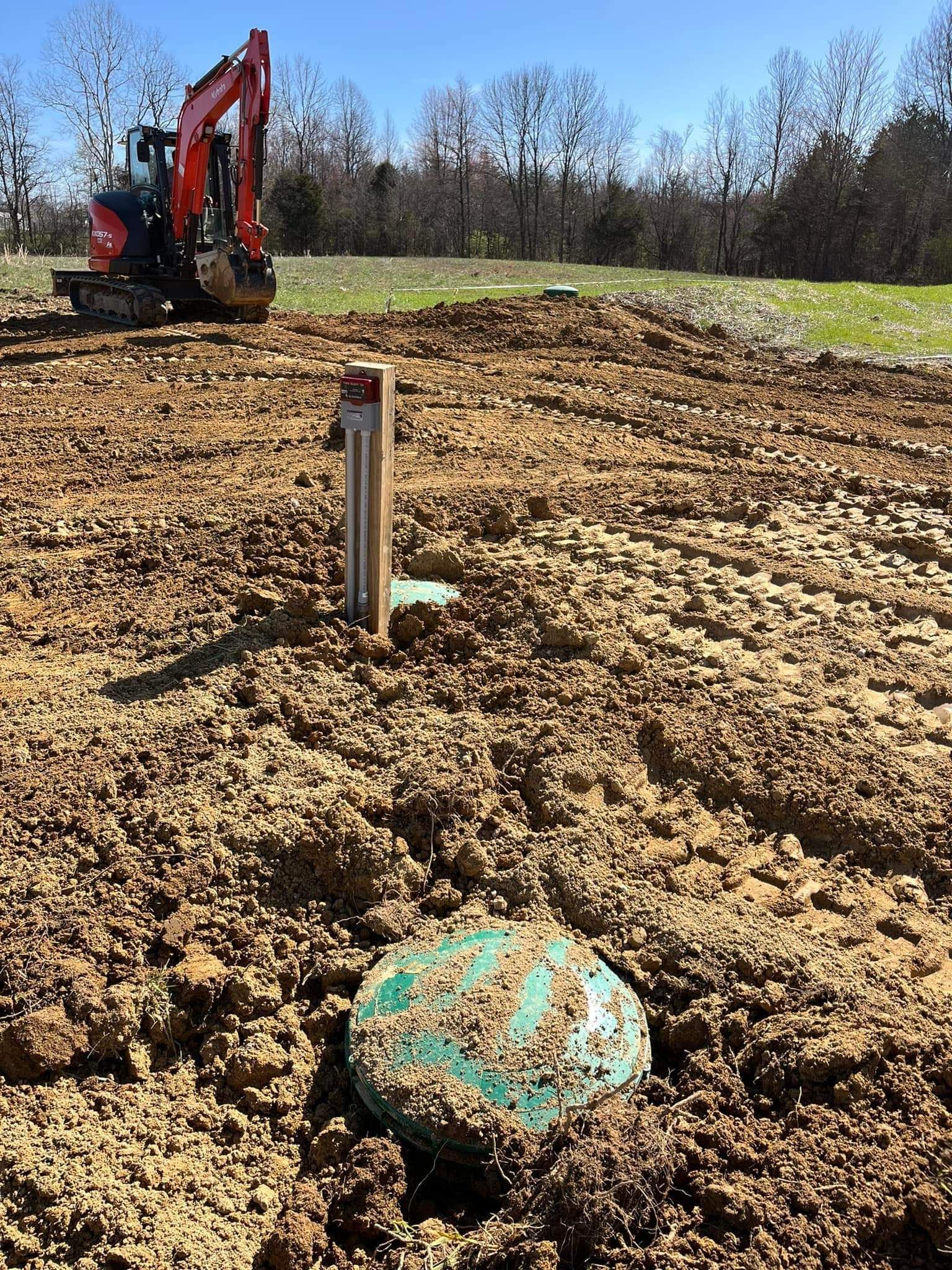 A large pile of dirt in a field with trees in the background.
