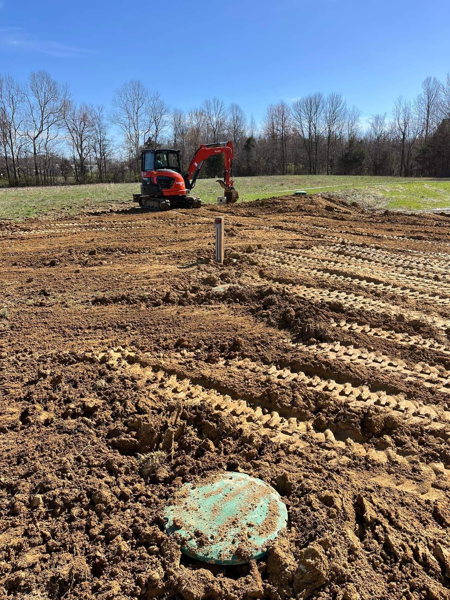A large pile of dirt in a field with trees in the background.