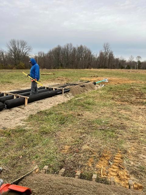 Man in a blue hoodie is standing in a field holding a tape measure - Campbellsburg, IN | Twisted Electric LLC 