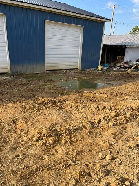 Puddle of water in the dirt in front of a blue garage door - Campbellsburg, IN | Twisted Electric LLC 