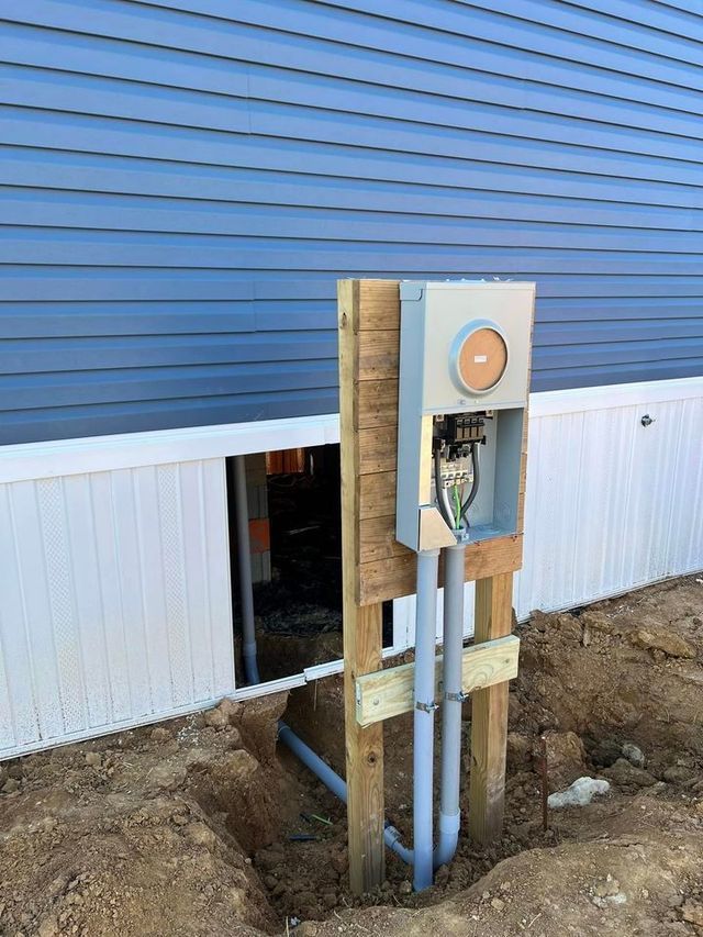 An Electrical Box Is Sitting on A Wooden Post Next to A House — Campbellsburg, IN — Twisted Electric LLC