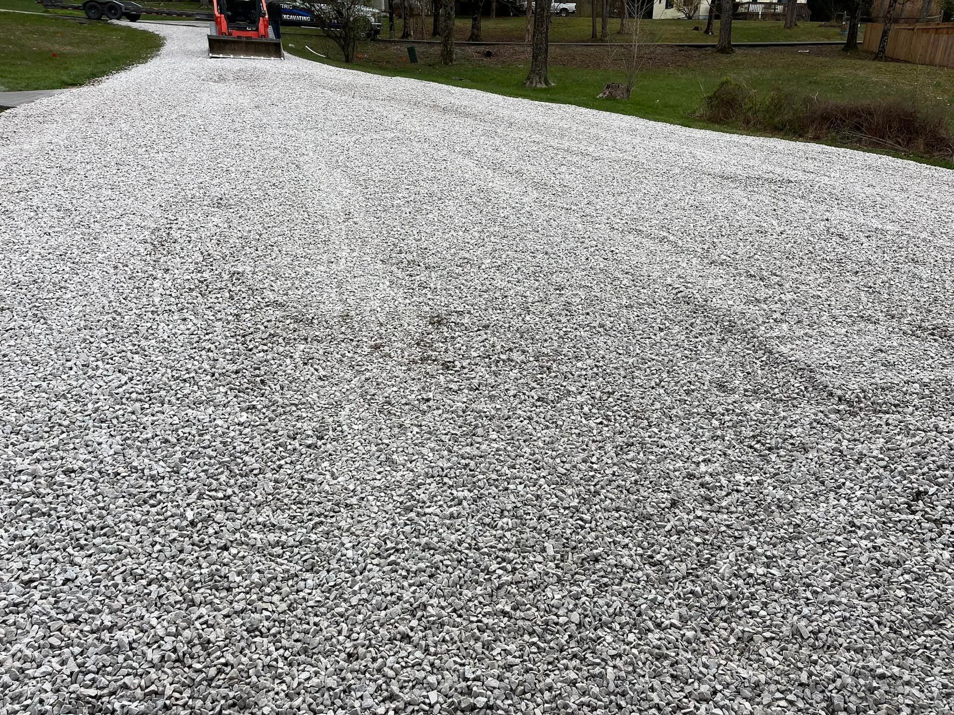 A gravel driveway with a tractor driving down it.