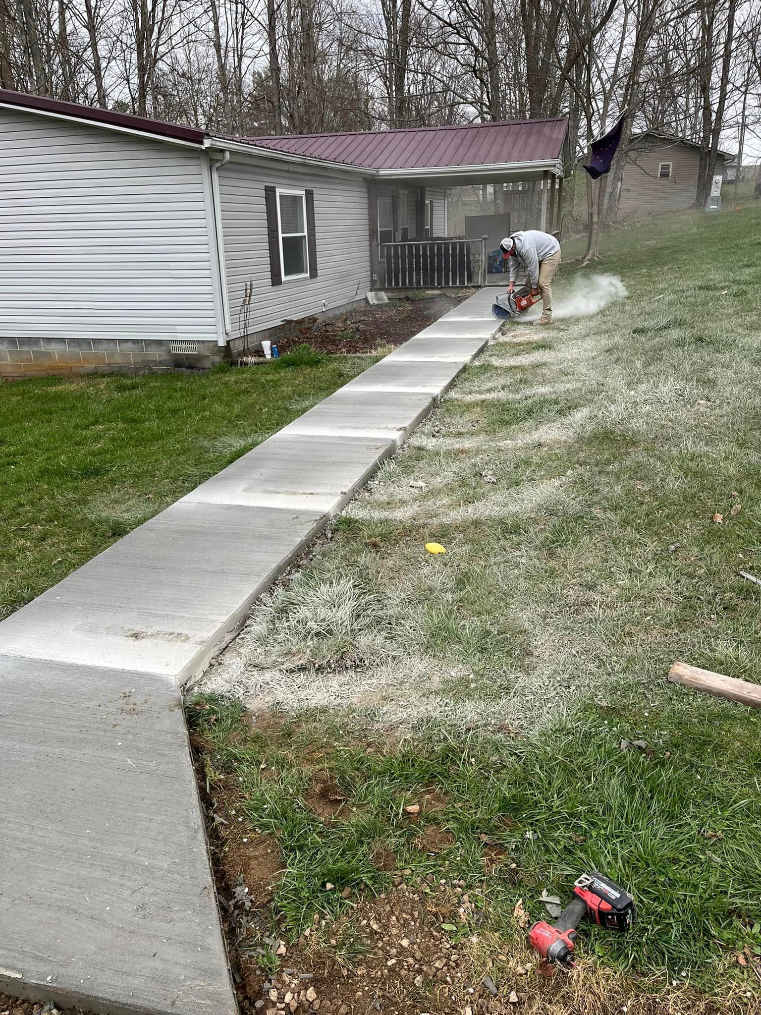 A man is working on a concrete walkway in front of a house.
