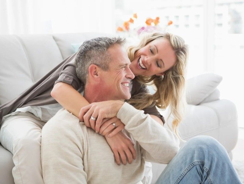 A woman is sitting on a couch and hugging a man