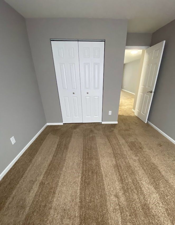 An empty bedroom with a closet and a carpeted floor.