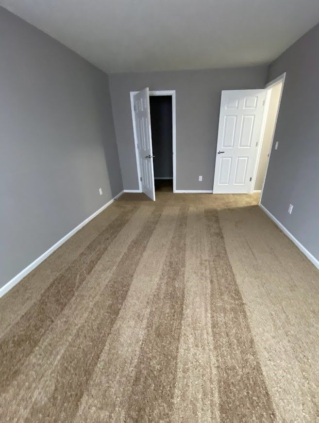 An empty room with a striped carpet and gray walls.