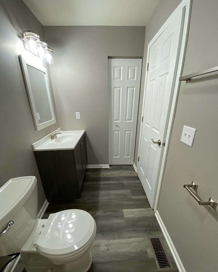 A bathroom with a toilet , sink and mirror.