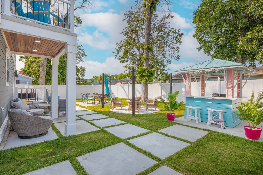 Backyard with patio, lawn, outdoor bar, seating areas, and a two-story balcony.