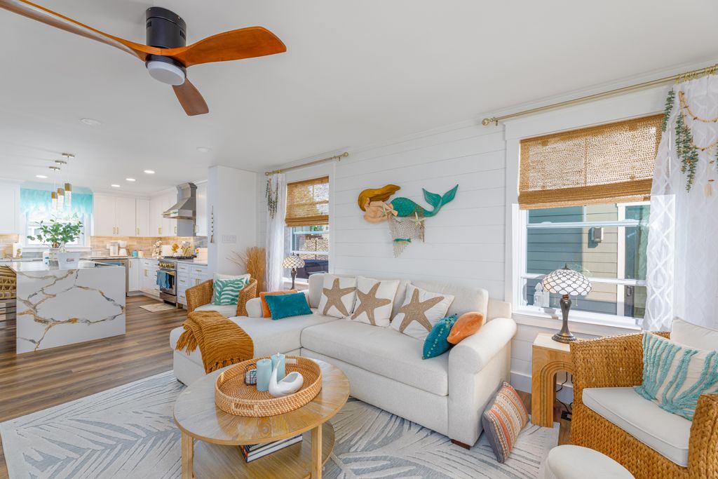 Living room with white walls, a white couch, and coastal decor.