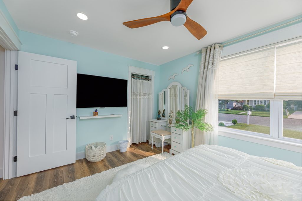 Bedroom with blue walls, wood ceiling fan, white door, and a window.