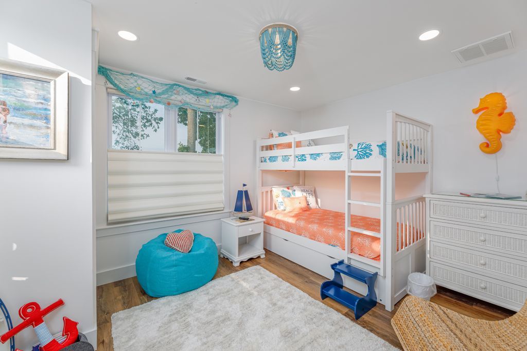 Coastal-themed bedroom with white bunk beds, teal accents, and an orange seahorse decoration.