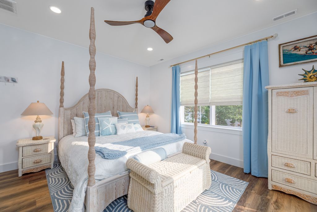 Bedroom with a four-poster bed, blue and white accents, and a ceiling fan.