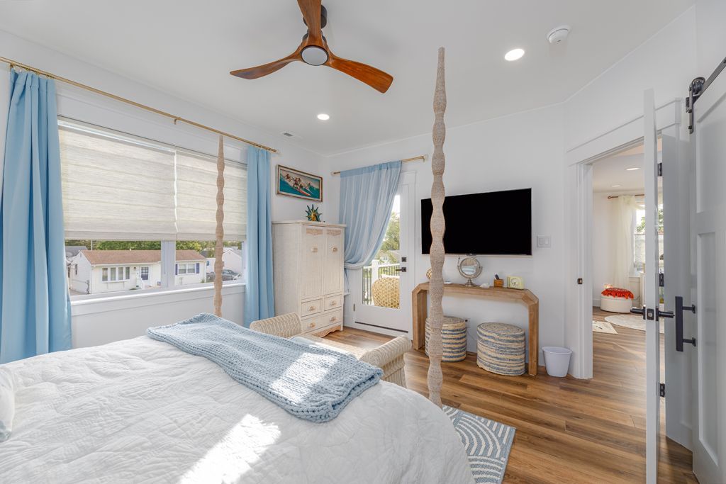 Bedroom with four-poster bed, blue curtains, white walls, and a view of outside.