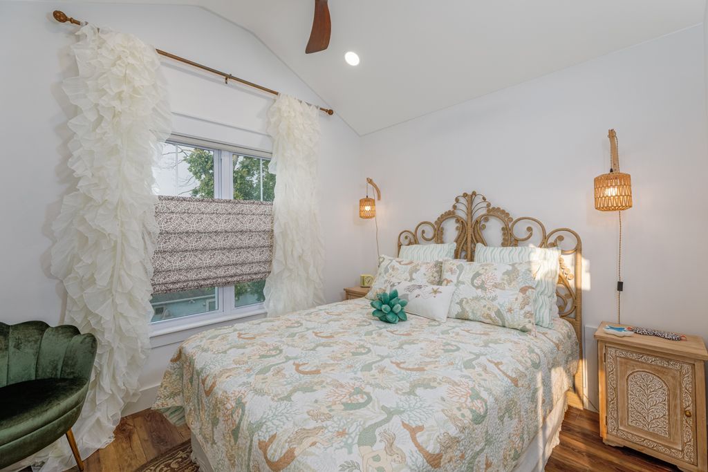 Bedroom with patterned bedspread, decorative headboard, and fringed curtains.