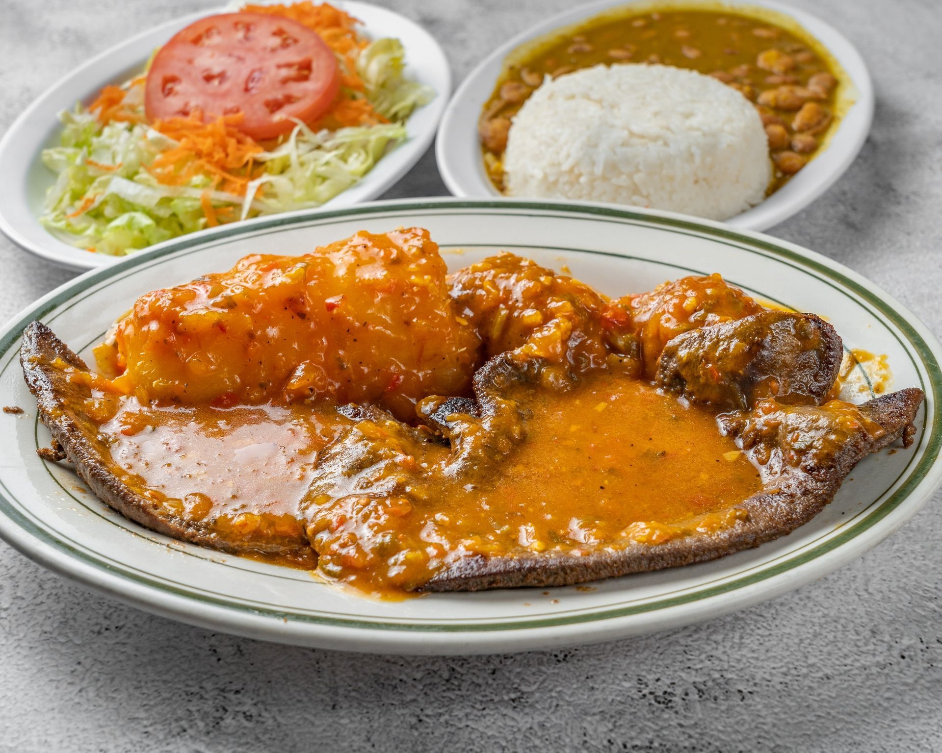 A plate of Colombian food with meat , sauce and rice on a table.