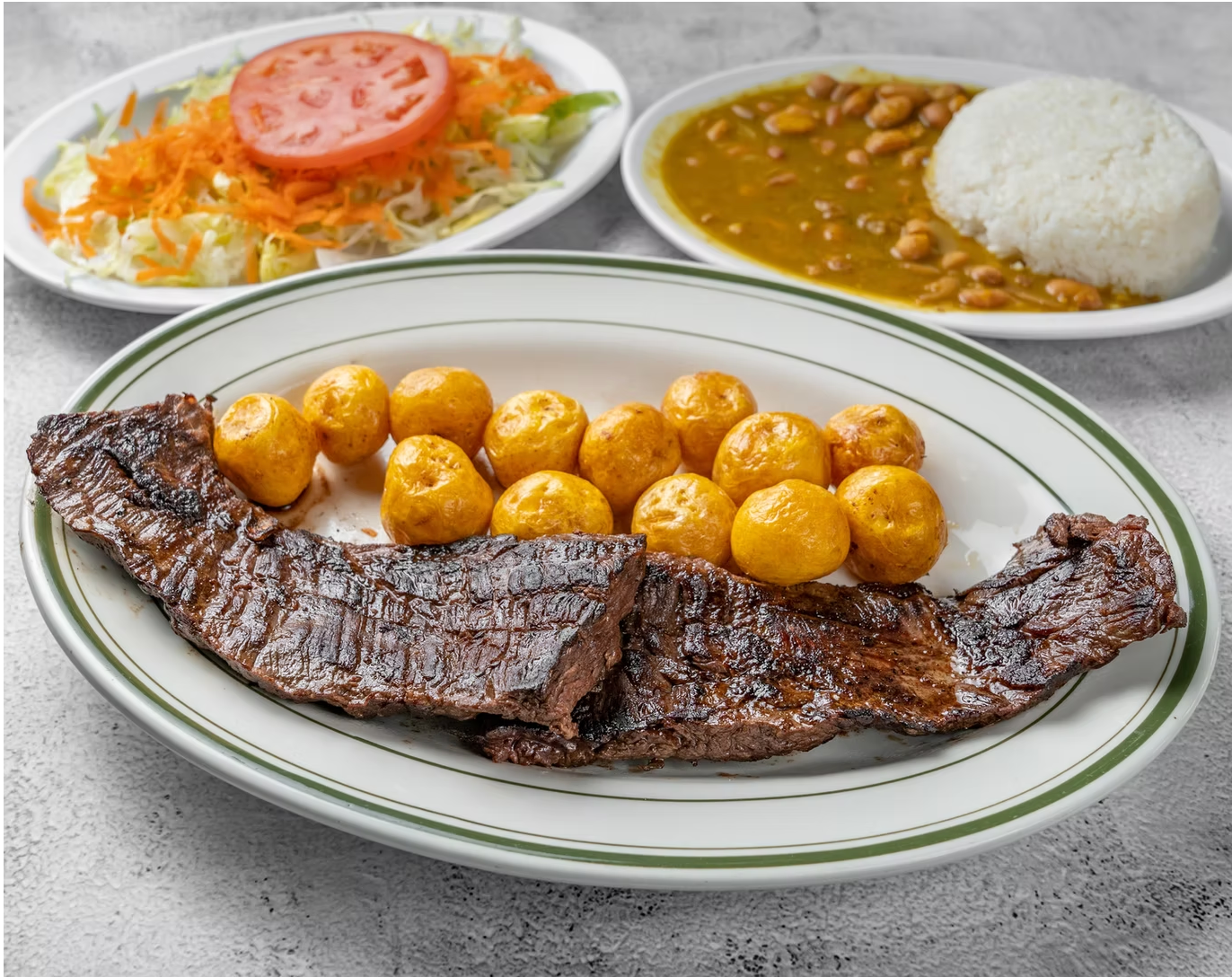 A plate of Colombian food with a steak and potatoes on it