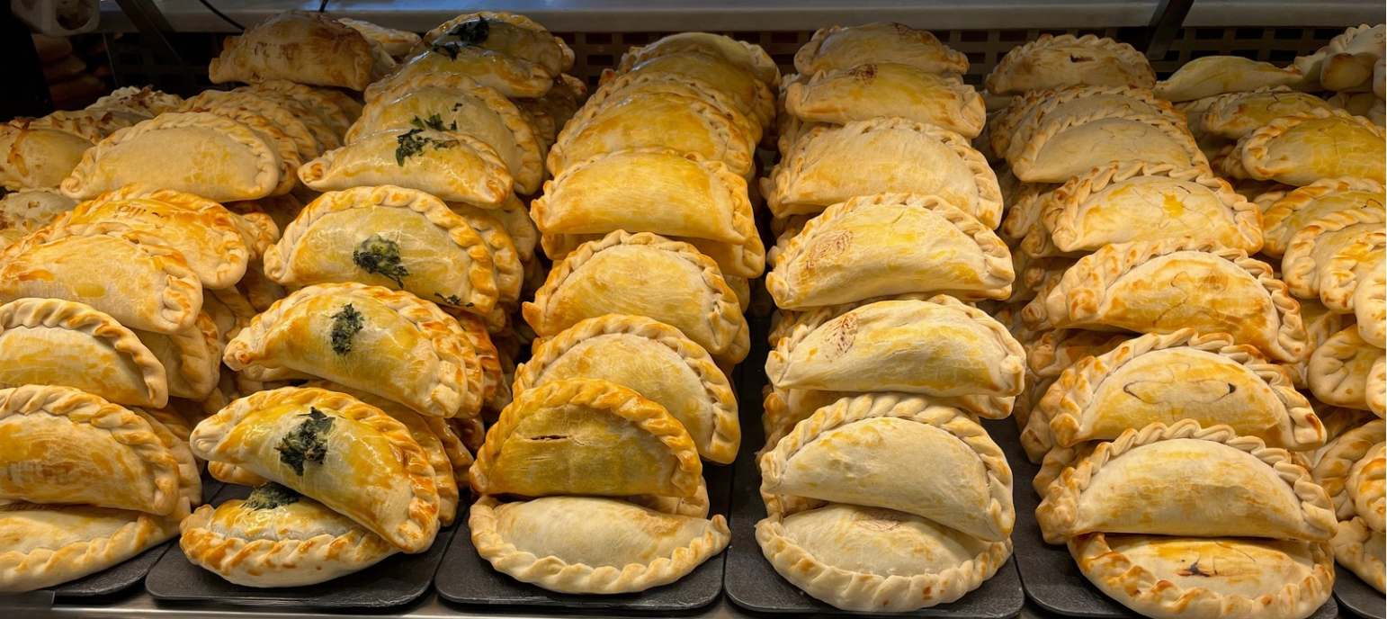 A bunch of empanadas are sitting on top of each other on a table.