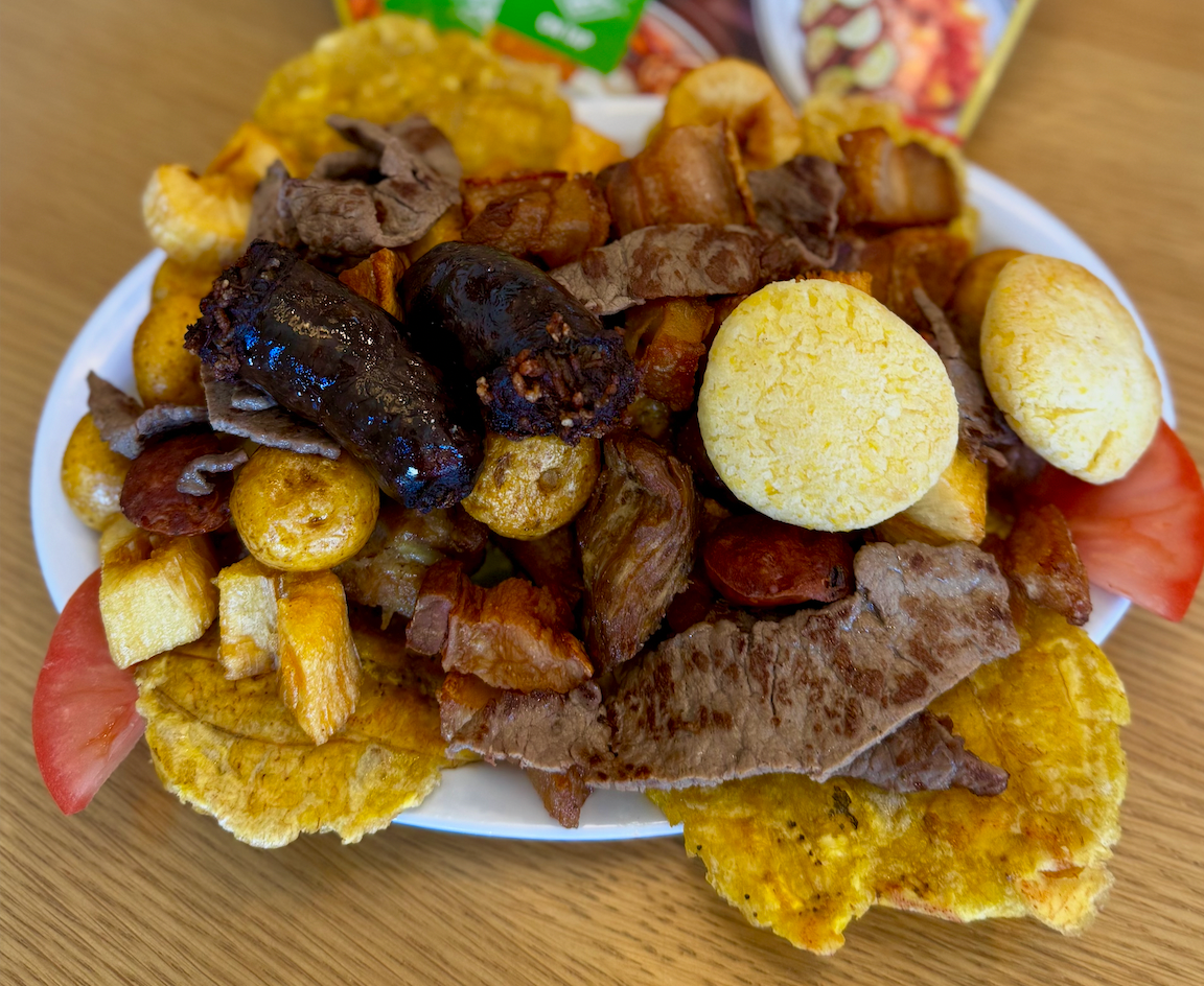 A white plate topped with a variety of Colombian food on a wooden table.