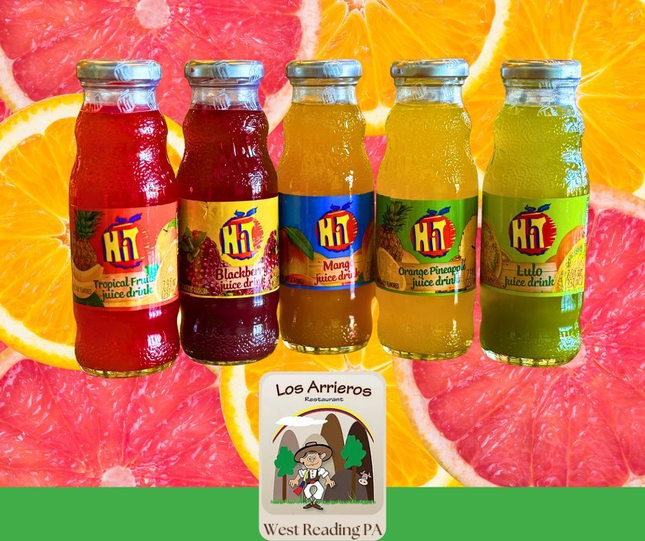 Four bottles of hit juice are lined up in front of slices of fruit