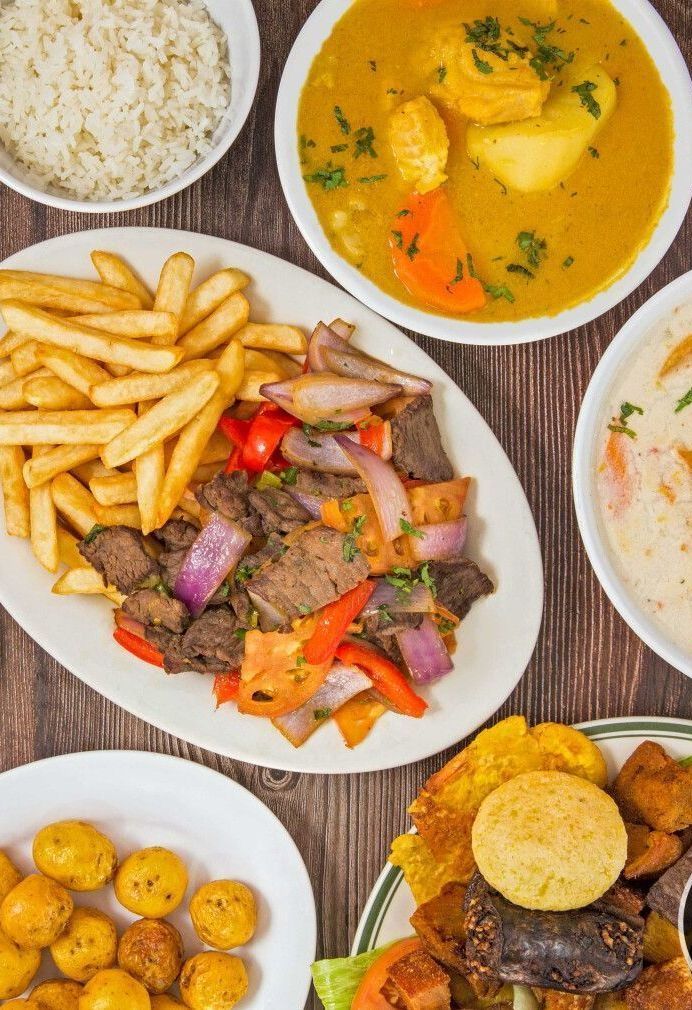 A table topped with plates of Colombian food and bowls of soup.