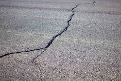 Close up of a single crack running down a section of  asphalt.