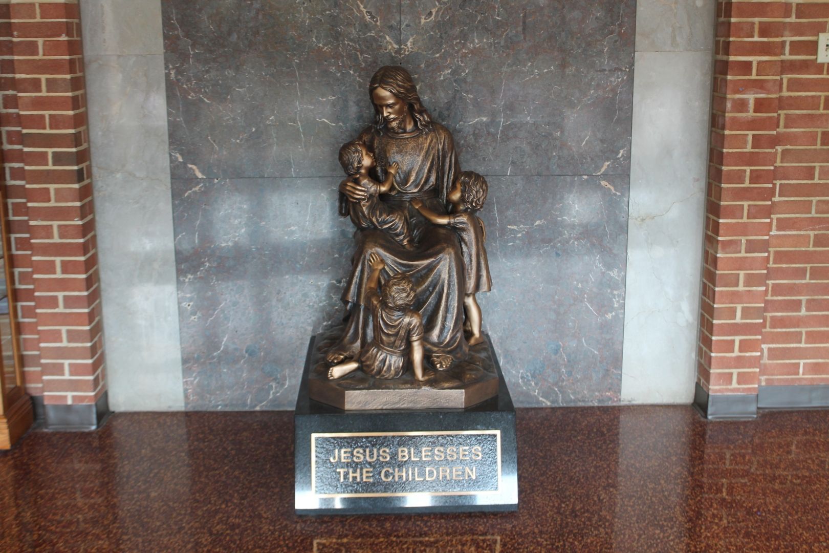 A statue of jesus holding a child with a sign that says
