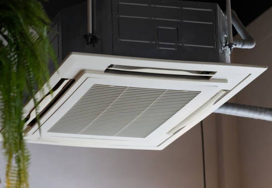 A man wearing a hard hat and goggles is standing in a room.