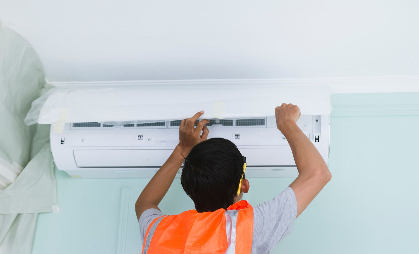 A man wearing a hard hat and goggles is standing in a room.