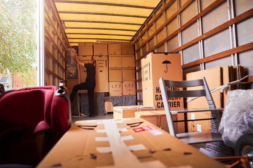 a man is loading boxes into a moving truck .