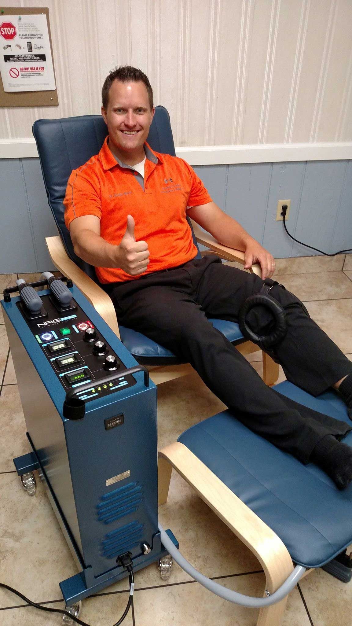 A man is sitting in a chair giving a thumbs up.