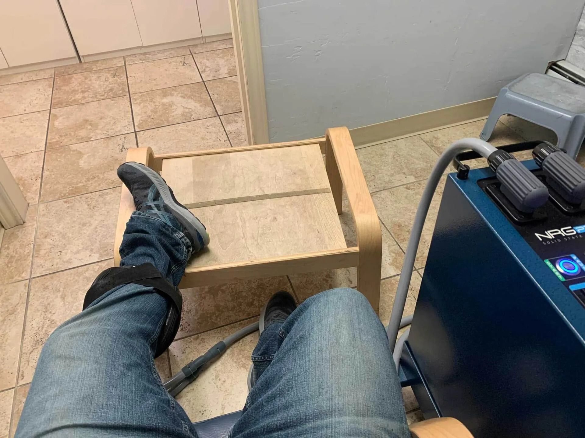 A person is sitting in a chair with their legs crossed in front of a machine.