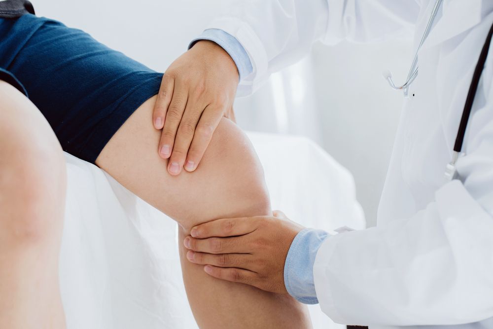 A doctor is examining a patient 's knee in a hospital.