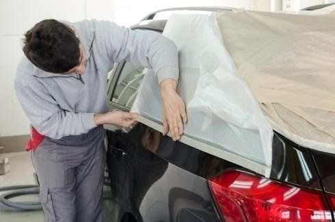 carrozziere mentre prepara un'auto prima della verniciatura