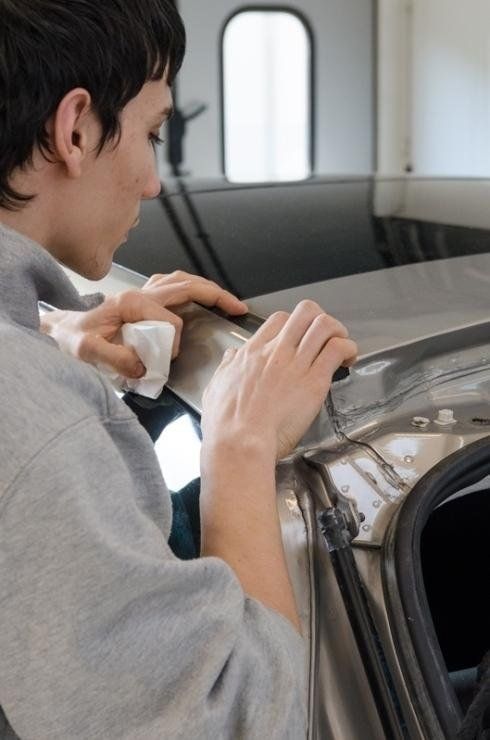 carrozziere mentre controlla la carrozzeria di un'auto