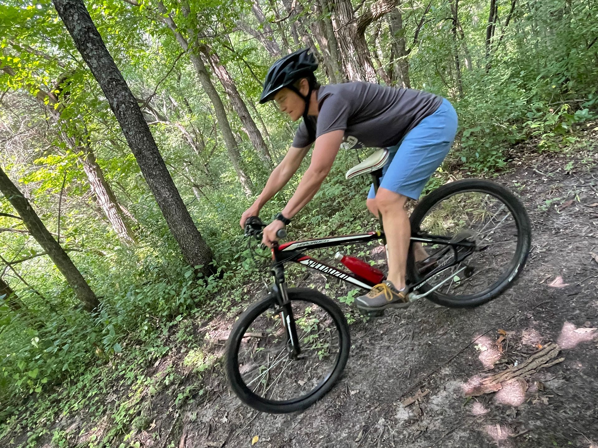 Mountain biker going downhill with butt behind seat to get weight back.