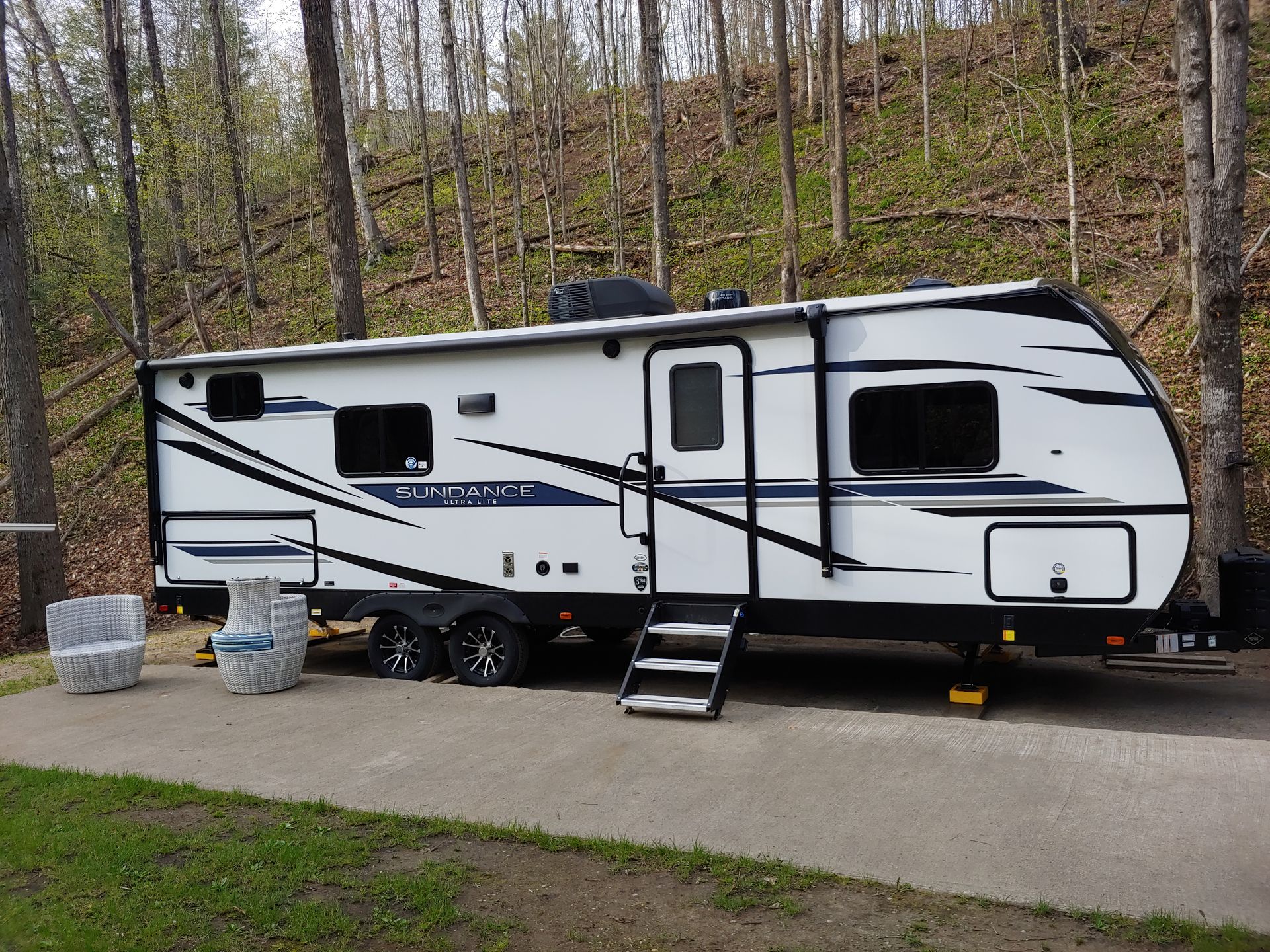A white trailer is parked on the side of a road in the woods.