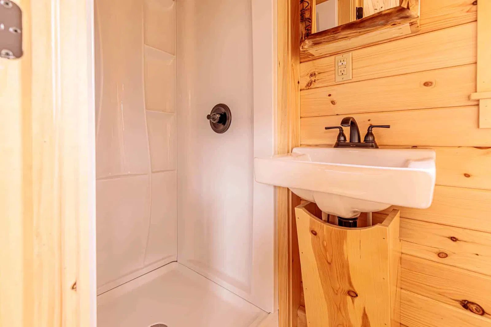 A bathroom with a sink , shower and mirror.