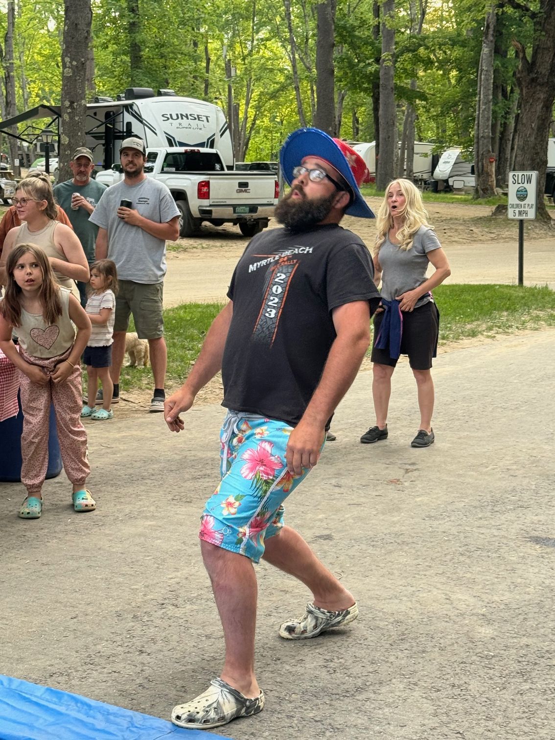 A man with a beard is dancing in front of a group of people.