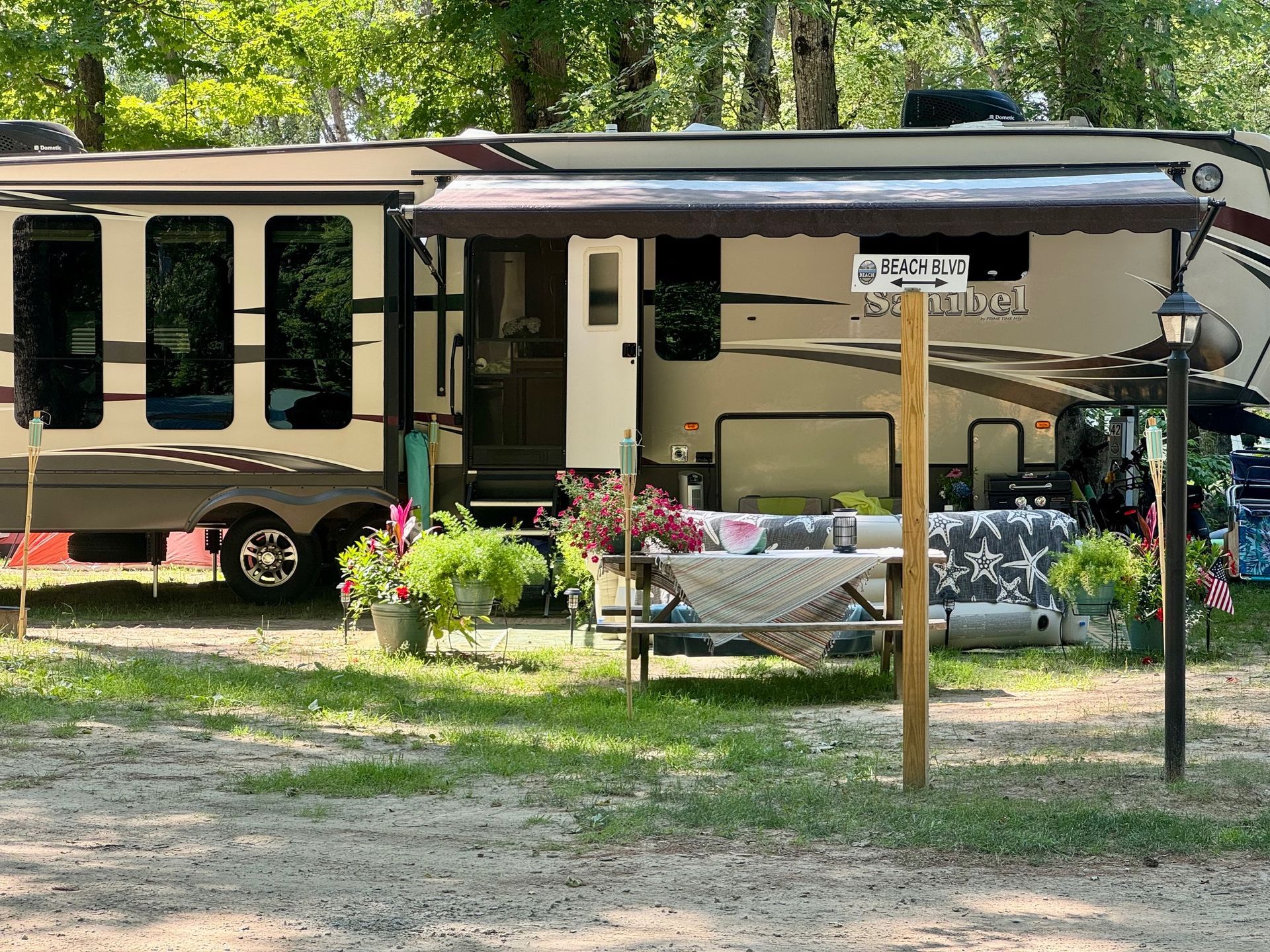 A rv is parked in a grassy area with a canopy over it.