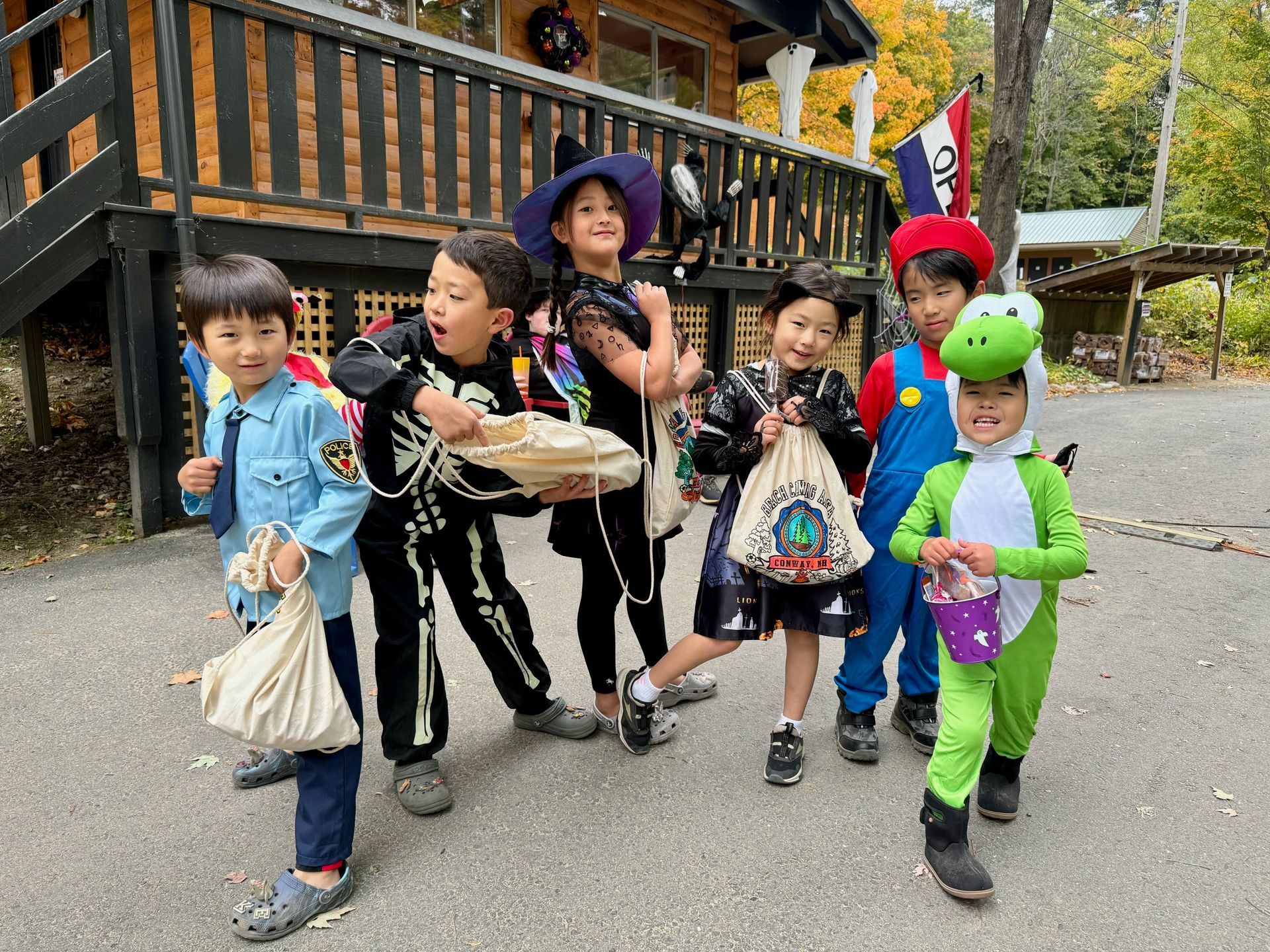 A group of children in halloween costumes are standing in front of a house.