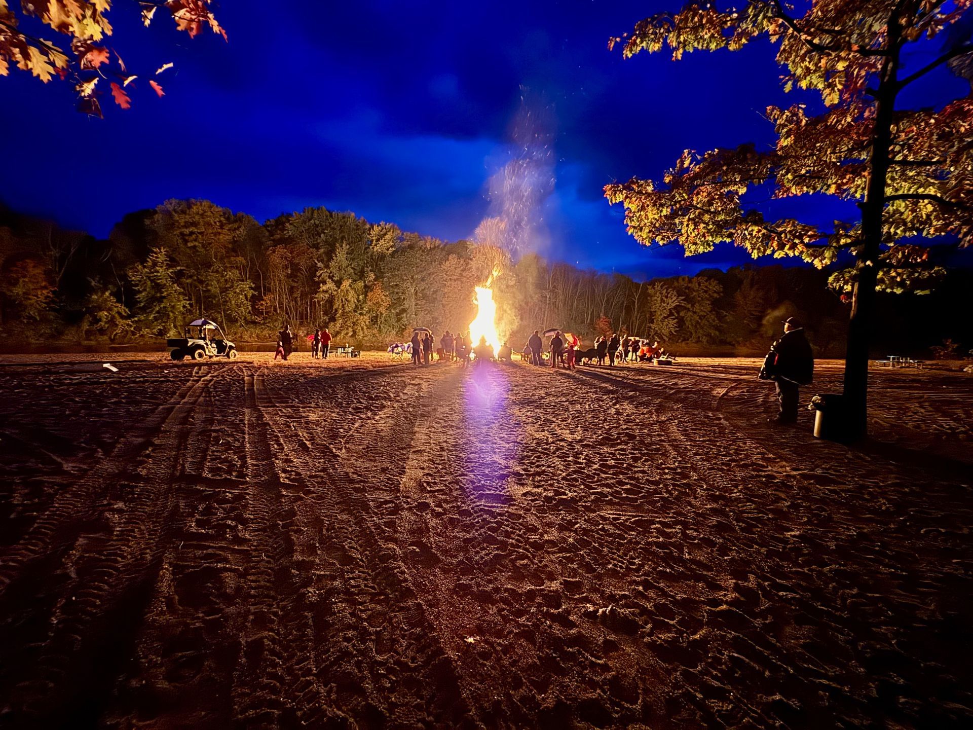 A group of people are gathered around a campfire at night.