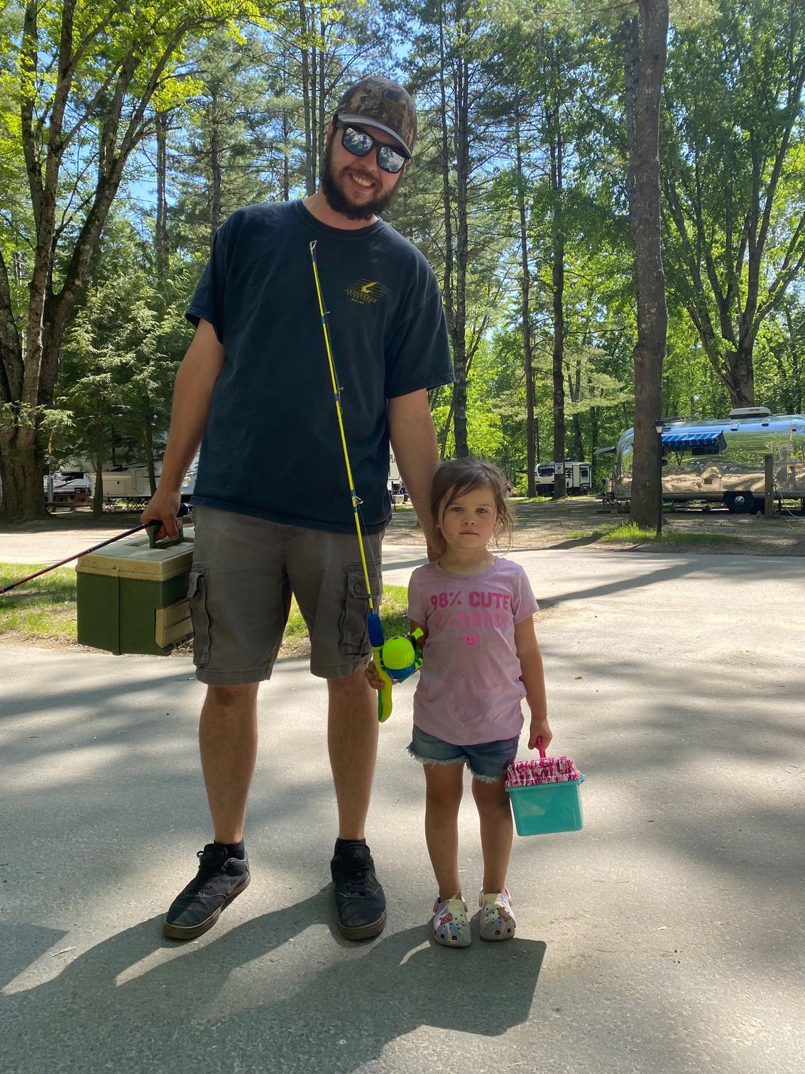 A man and a little girl are standing next to each other in a parking lot.