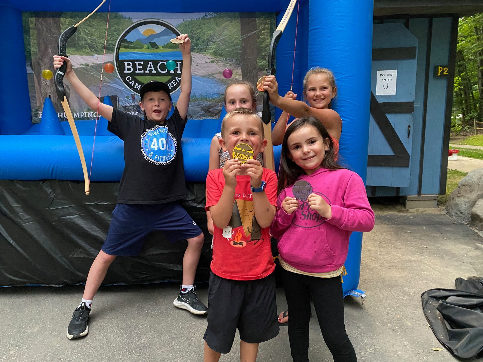 A group of children are posing for a picture in front of a bouncy house.