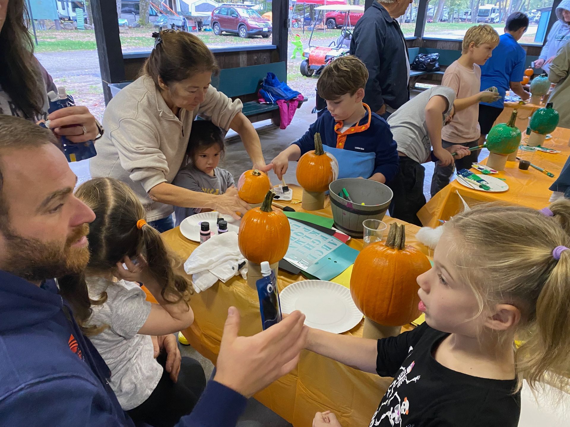 A group of people are sitting at a table carving pumpkins.