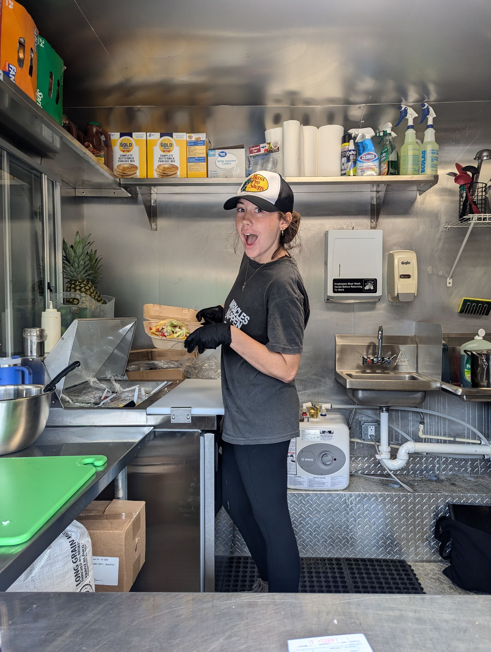 A woman is standing in a kitchen holding a spray bottle.