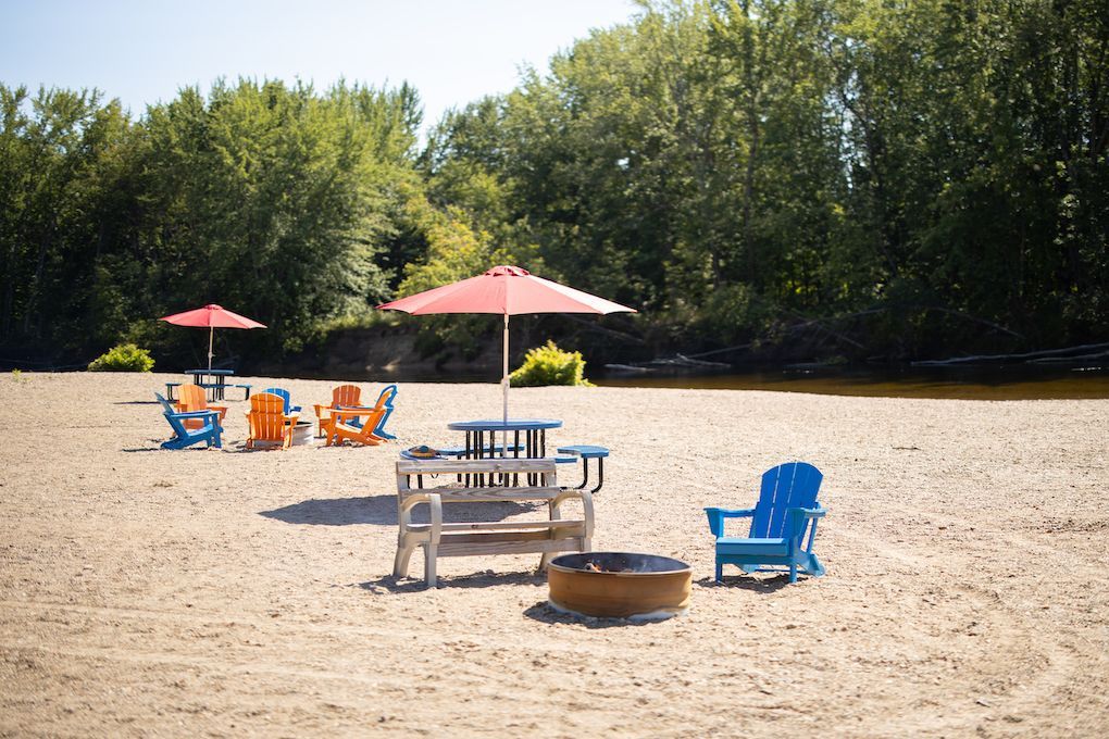 A picnic table and chairs are sitting on a sandy beach next to a fire pit.