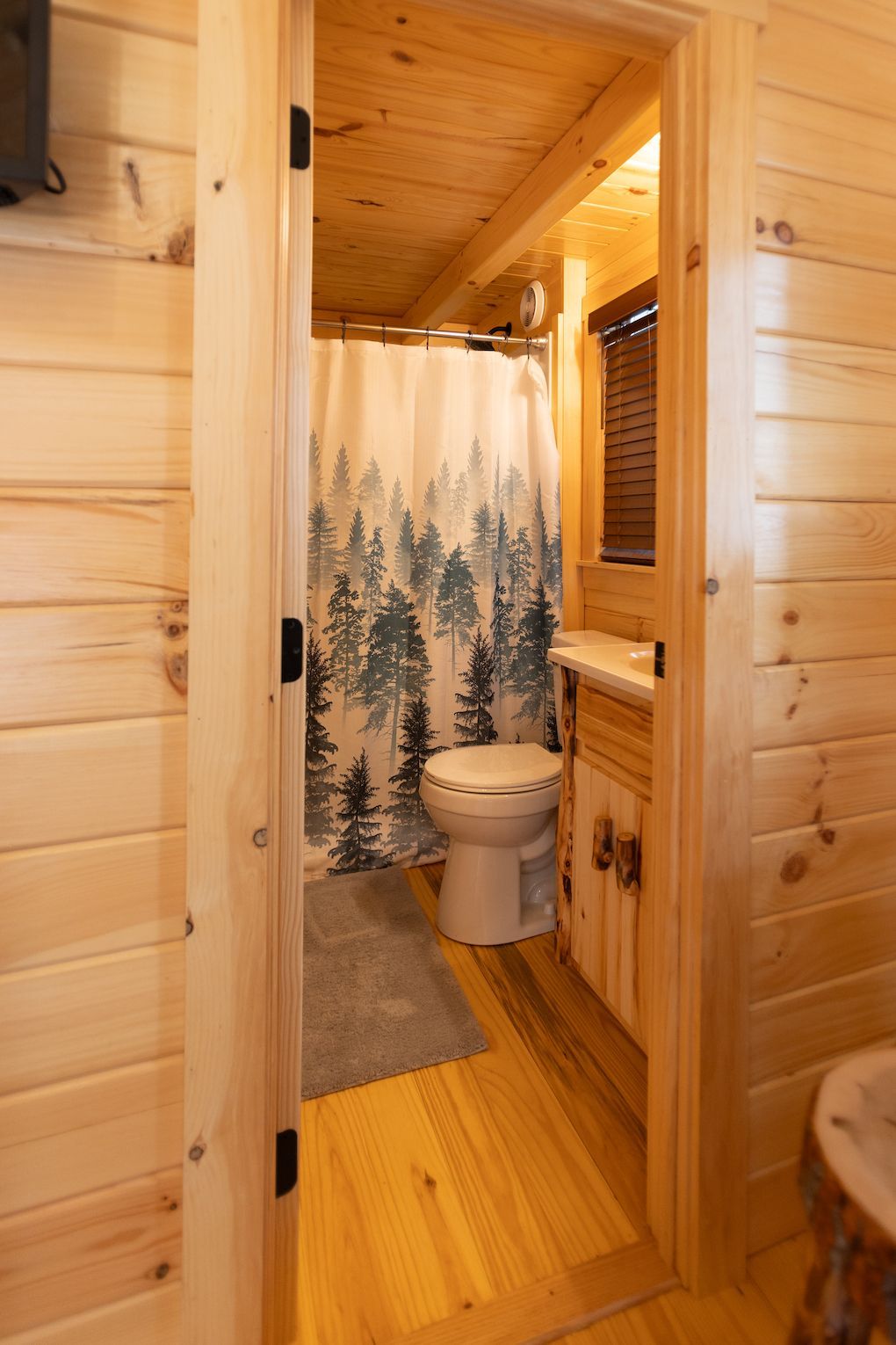 A bathroom in a log cabin with a toilet and shower curtain.